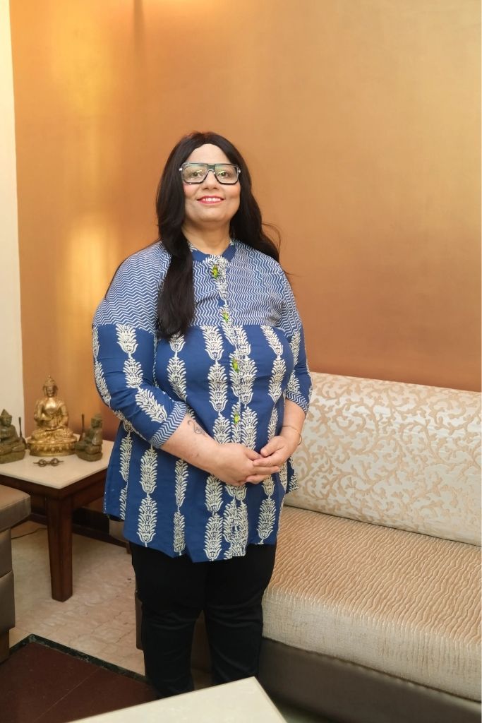 Woman standing by couch smiling, parenting coach Sarita Chugh